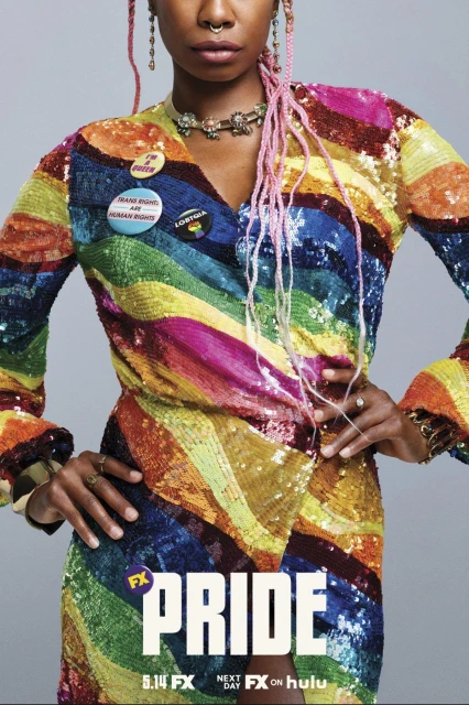 Close-up of a Black woman in a rainbow sequin dress adorned with buttons, paired with pink hair and jewelry, set against a gray backdrop.