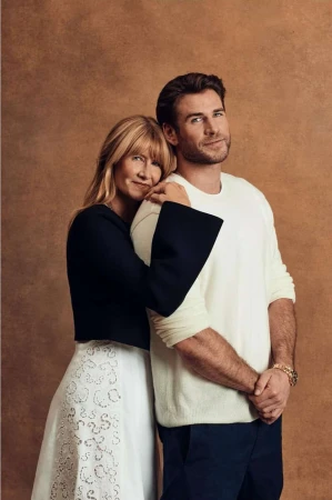 Portrait of adult male and adult female, arm around shoulder, wearing formal wear against a solid brown backdrop in a photo studio.