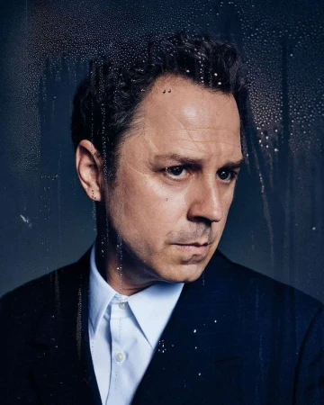 Portrait of a man in a dark suit and white shirt viewed through a wet glass window by Leigh Keily
