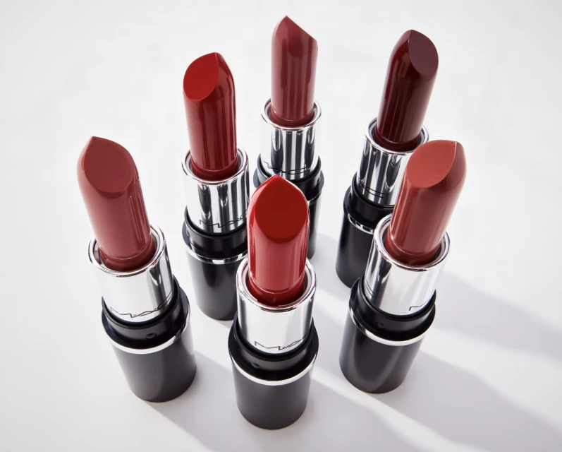Assortment of red lipsticks with silver and black tubes arranged on a white surface, suitable for beauty or cosmetic themes.