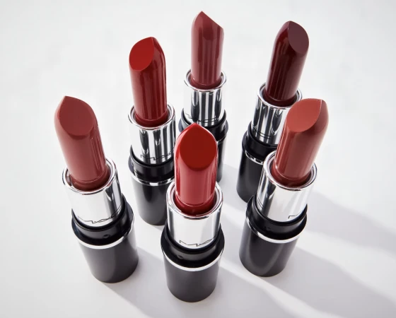 Assortment of red lipsticks with silver and black tubes arranged on a white surface, suitable for beauty or cosmetic themes.
