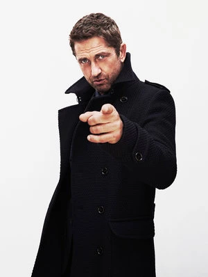 Adult male with brown hair, wearing a black coat, pointing directly at the viewer in a studio shot against a white background.