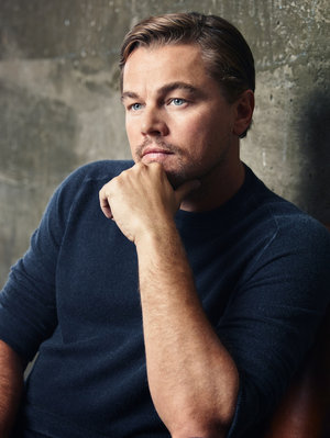 Portrait of a fair-skinned adult male with blue eyes, wearing a dark blue sweater, with his hand resting on his chin.