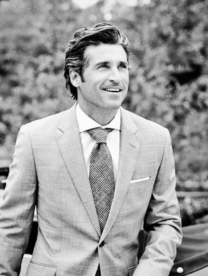 Portrait of Patrick Dempsey in a tailored grey suit and patterned tie outdoors in New York