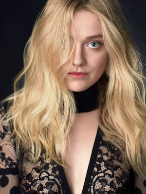 Blonde woman with blue eyes posing in black lace top with dark background, soft lighting, face forward, hair partially covering face.