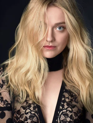 Blonde woman with blue eyes posing in black lace top with dark background, soft lighting, face forward, hair partially covering face.