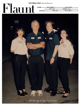 Four people standing outdoors at night on an asphalt street, wearing matching short-sleeved shirts and black trousers, featured on a magazine cover.