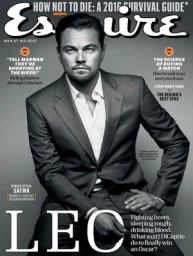 Leonardo DiCaprio wearing a tailored grey suit and white dress shirt against a plain grey background on a magazine cover.