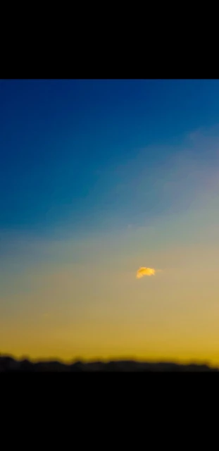 Sky at sunset features a gradient of deep blue to golden yellow, with soft clouds adding depth and texture to the vibrant atmospheric scene.