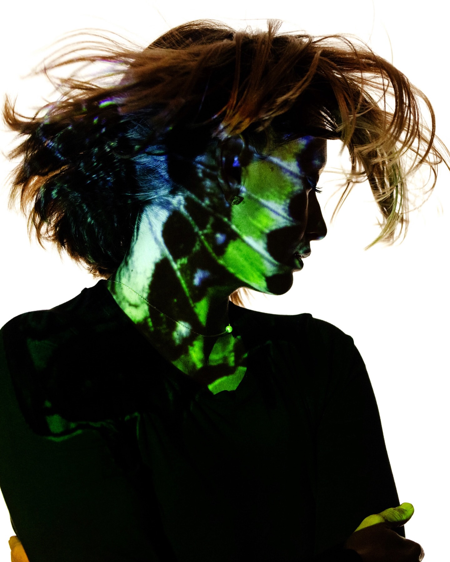 Portrait of a woman with butterfly image projected onto her face, against a white background, creating a striking and artistic effect.