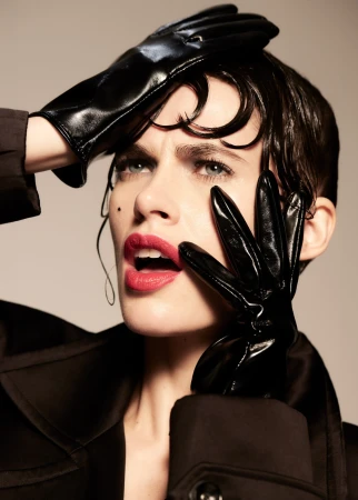Close-up portrait of a woman wearing black shiny leather gloves and dark coat with glossy wet hair and bold red lips by Frankie Batista.