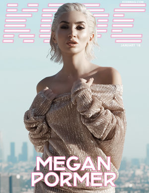 Magazine cover featuring a blonde model in a shimmering gold dress, set against a cityscape backdrop under a clear sky, with bold title text.