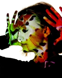 Profile portrait of a woman with colorful projection mapping on her face and hands against a white background