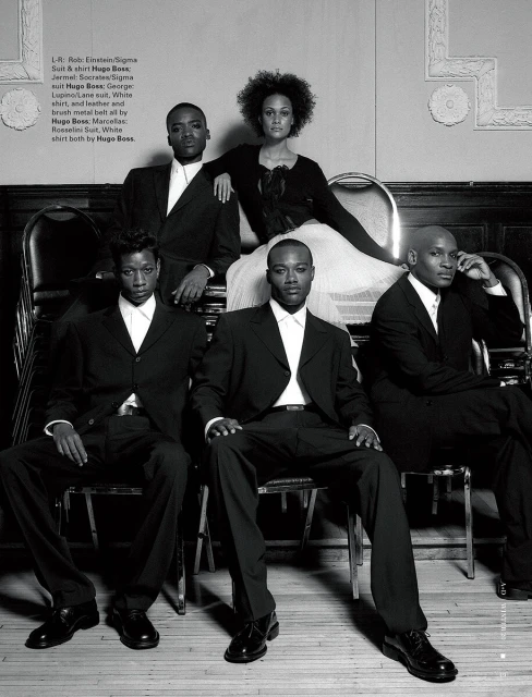 Monochrome fashion shoot featuring a group of four men and a woman wearing formal black suits and dress sitting on chairs.