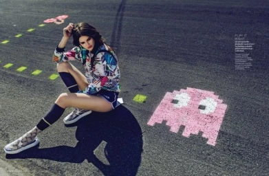Model seated on asphalt with painted arcade ghost graphics wearing patterned jacket and shorts