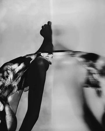 Black and white image of a person's leg extended with foot in frame, set against a neutral background.