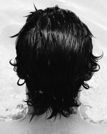 Close-up back of head of person with wet dark hair in water by Omar Cruz
