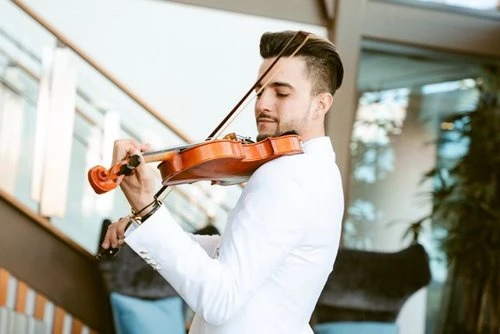 Man in white suit playing a violin outdoors, fair lighting, medium shot, musician performing, classical music, outdoor concert.