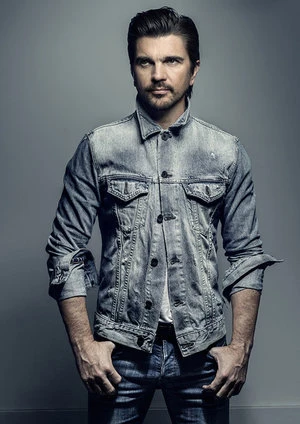 Portrait of a handsome man in a denim jacket and jeans against a grey backdrop, showcasing fashion and style with a neutral expression.