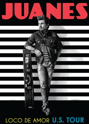 Promotional image of Juanes wearing a denim jacket, jeans, and a striped shirt while leaning against a guitar case.
