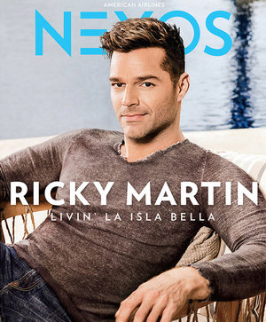Ricky Martin poses on the cover of Nexos magazine, wearing a gray sweater and seated in a wicker chair against a blurred background.