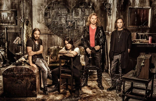 Group shot of four adult males in dark clothing posing in a room with worn walls and vintage furnishings, creating a moody atmosphere.