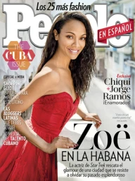 Zoe Saldana wearing a strapless red dress leaning on a white railing outdoors on a sunny day