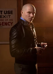 Portrait of musician Maury Hechavarria wearing a black leather jacket and holding glasses indoors
