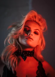 Portrait of a blonde woman wearing a black polka dot neck scarf, lit by dramatic red lighting in Los Angeles