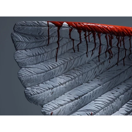Close-up of a white, feathered angel wing with red liquid dripping down, creating a dramatic and slightly unsettling visual.