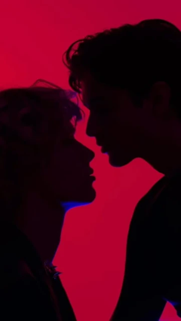 Silhouette of two people with a red background, showing profiles and suggesting a romantic or intimate moment, dark hair.