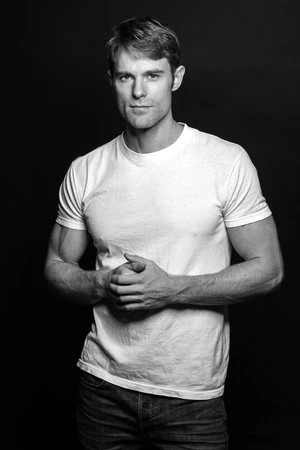 Portrait of a man in a white t-shirt standing against a dark background, photographed by Alvin Nguyen.