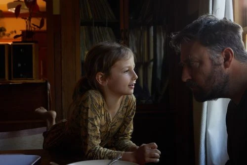 A young girl talking with an adult man in a domestic interior by photographer Douglas Adesko