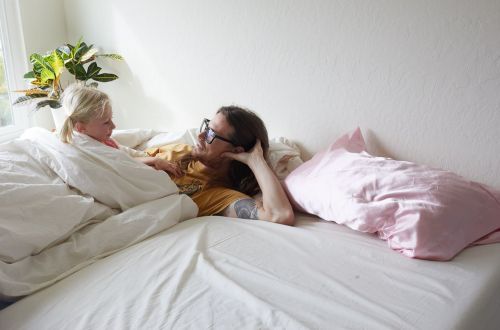 Mother and young child bonding in bed with sunlight and indoor plants. A family moment with love, relaxation, and affection.