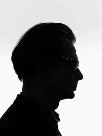 Profile silhouette of a man wearing eyeglasses against a bright white background
