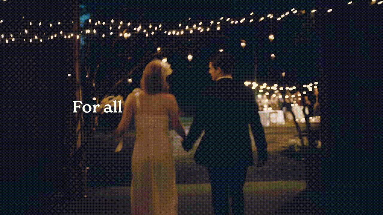 Silhouetted couple walks away hand-in-hand at night toward wedding reception. String lights and dining tables in background.