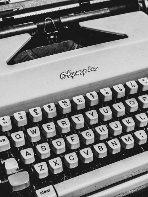 Close-up of a vintage Olympia typewriter with visible keys and brand name, in a black and white composition, showcasing a retro aesthetic.