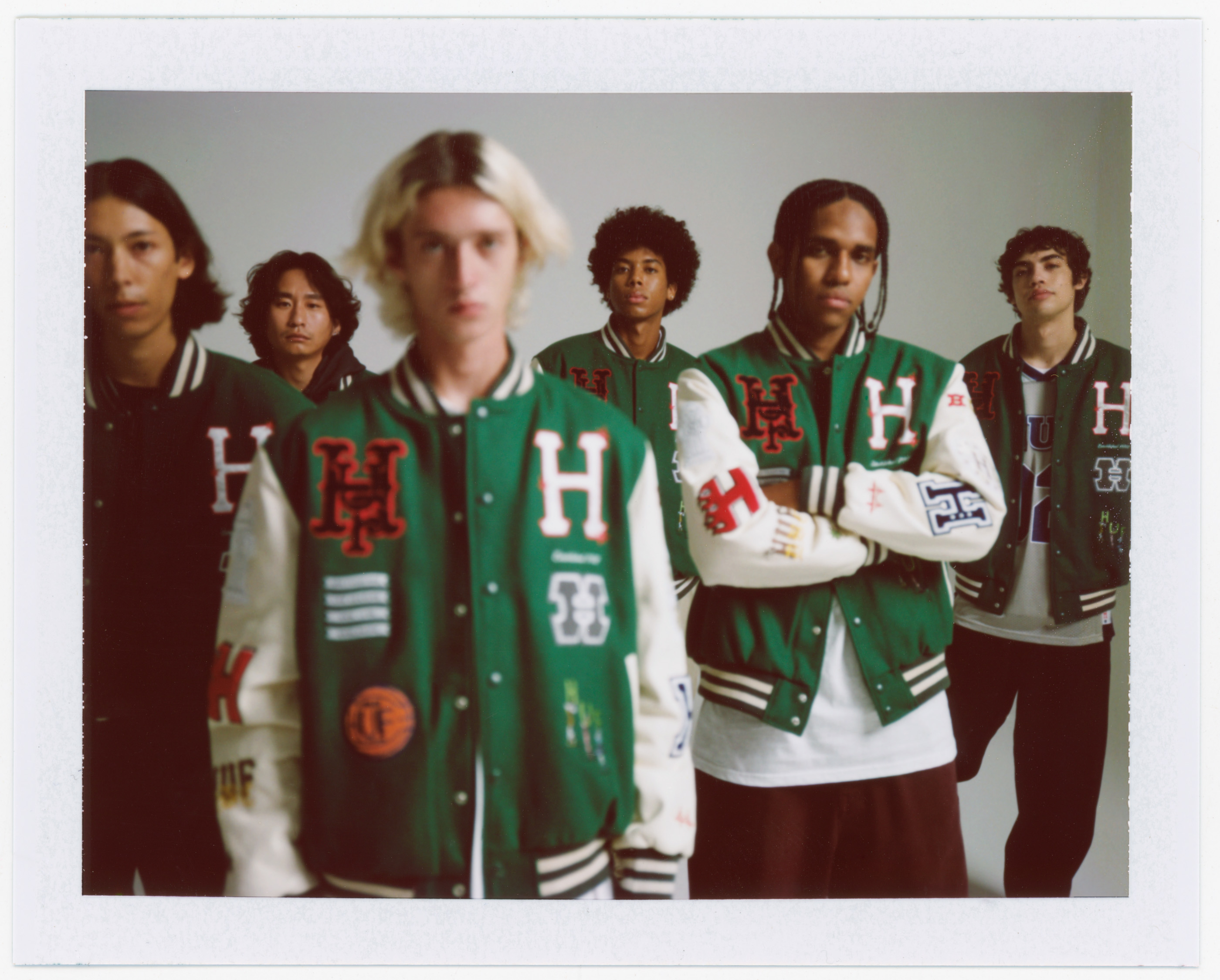 Group of young adult models wearing letterman jackets in a studio setting, showcasing fashion and casual wear.