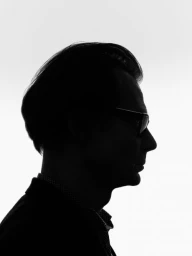 Profile silhouette of a man wearing eyeglasses against a bright white background