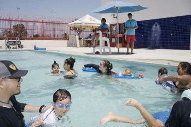 Children and instructors swimming and playing in an outdoor pool in Los Angeles, photographed by Gabriella Angotti-jones.