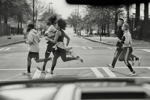 Group of runners jogging across a city street captured from inside a vehicle by Cole Barash