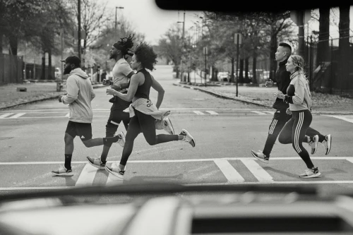 Group of runners jogging across a city street captured from inside a vehicle by Cole Barash