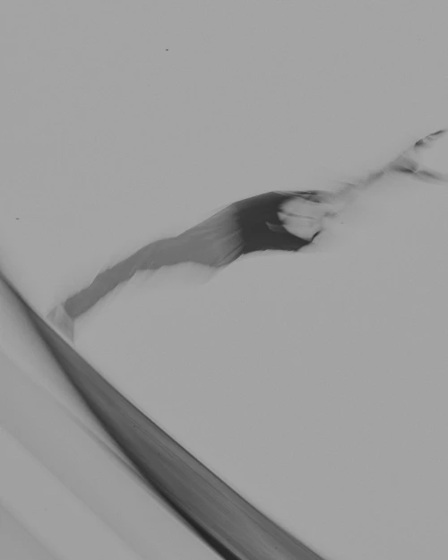 Abstract black-and-white photograph featuring a blurry human figure against a stark background, highlighting movement and form.