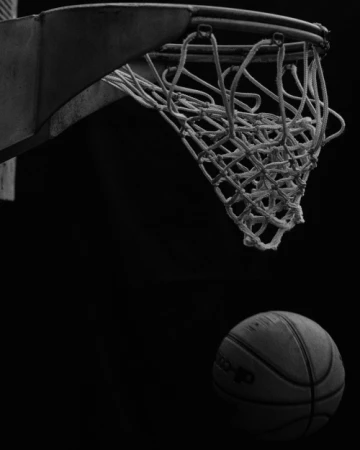 Basketball falling toward a net under dramatic low-key lighting captured by Cole Barash