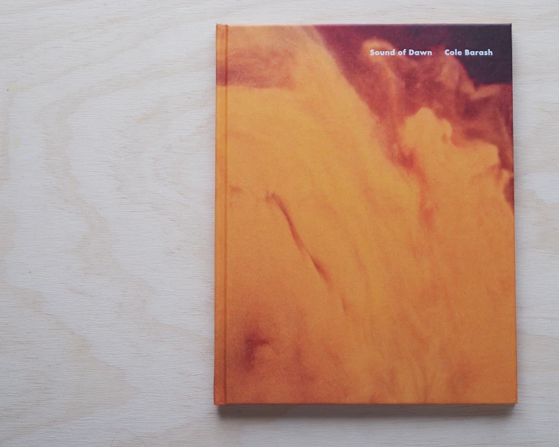 Book cover featuring a blurred abstract design in shades of orange and brown. The title 'Sound of Dawn' by Cole Barash is visible.