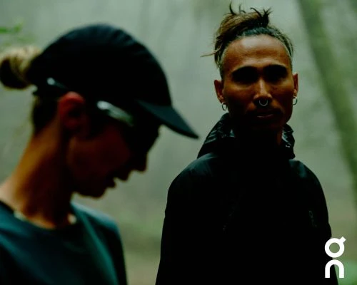 Two men with hair in top knots outdoors in a foggy forest setting, photographed by Cole Barash.