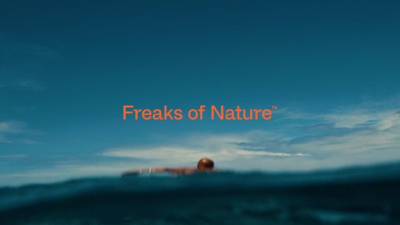 Person swimming in the ocean under a blue sky with the orange text overlay 'Freaks of Nature'.