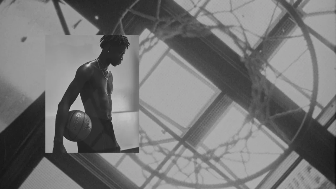 Monochrome portrait of an athletic man holding a basketball, showcasing athletic physique against an abstract linear background.