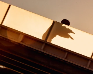 Strong shadow cast of a person on a warm-toned concrete architectural wall with layered horizontal beams