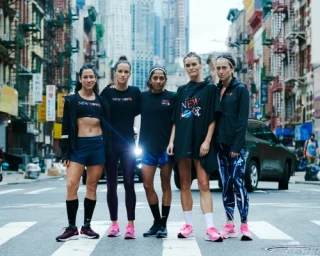 Five female runners posing together on a New York City street wearing athletic apparel and running shoes by Cole Barash